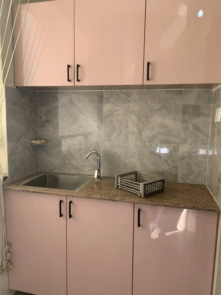 Pink kitchen cabinets with a stone backsplash