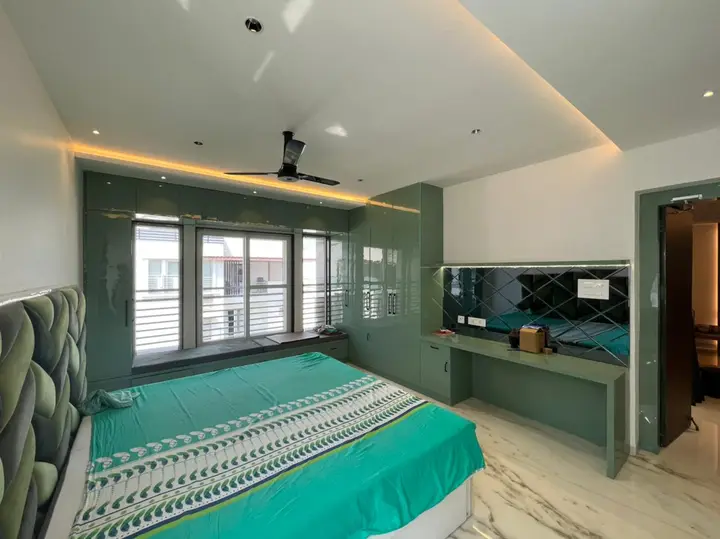 Guest bedroom with a green desk wall and teal bedding