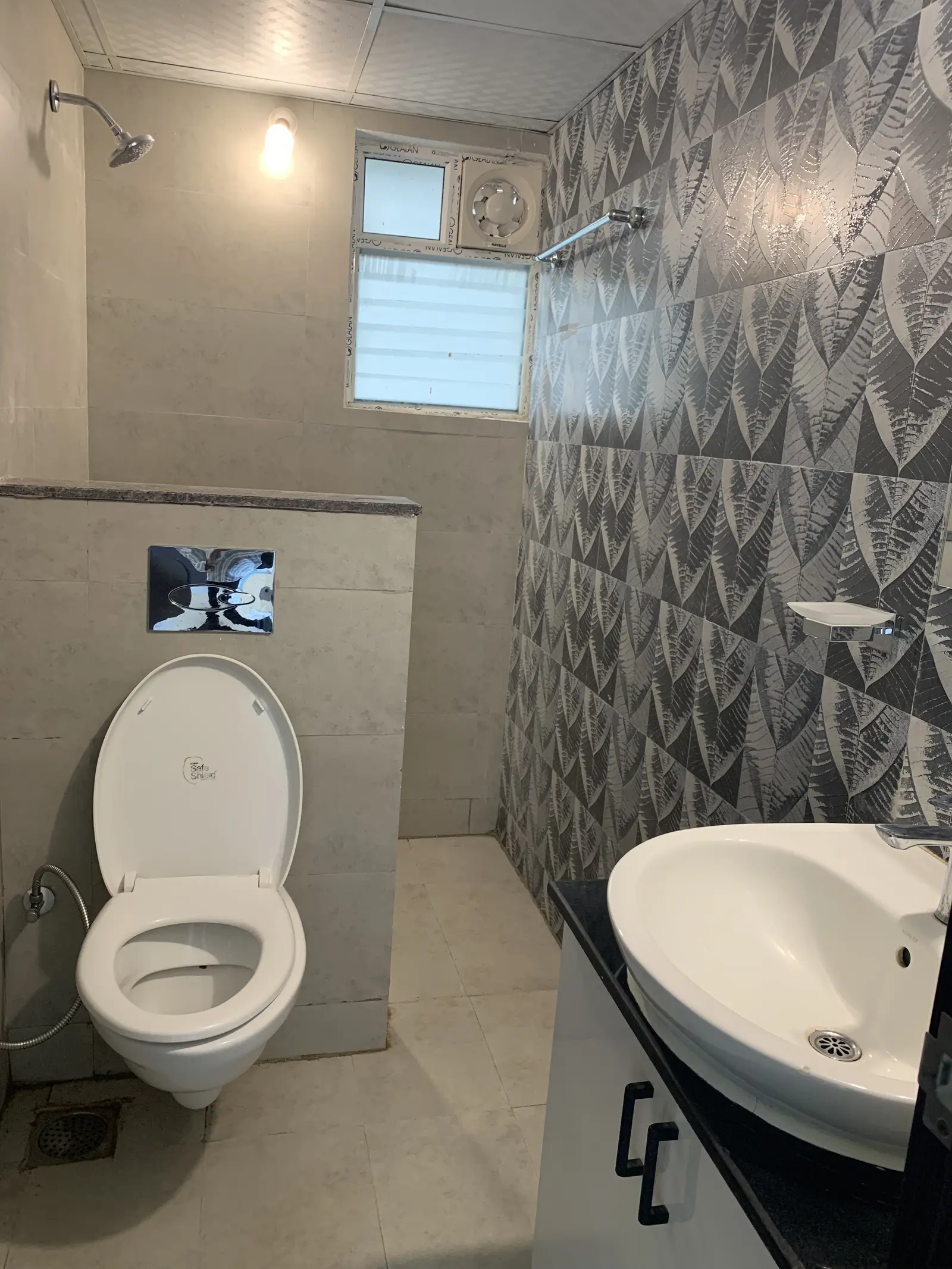 Bathroom with patterned wall tiles and a wall-hung toilet