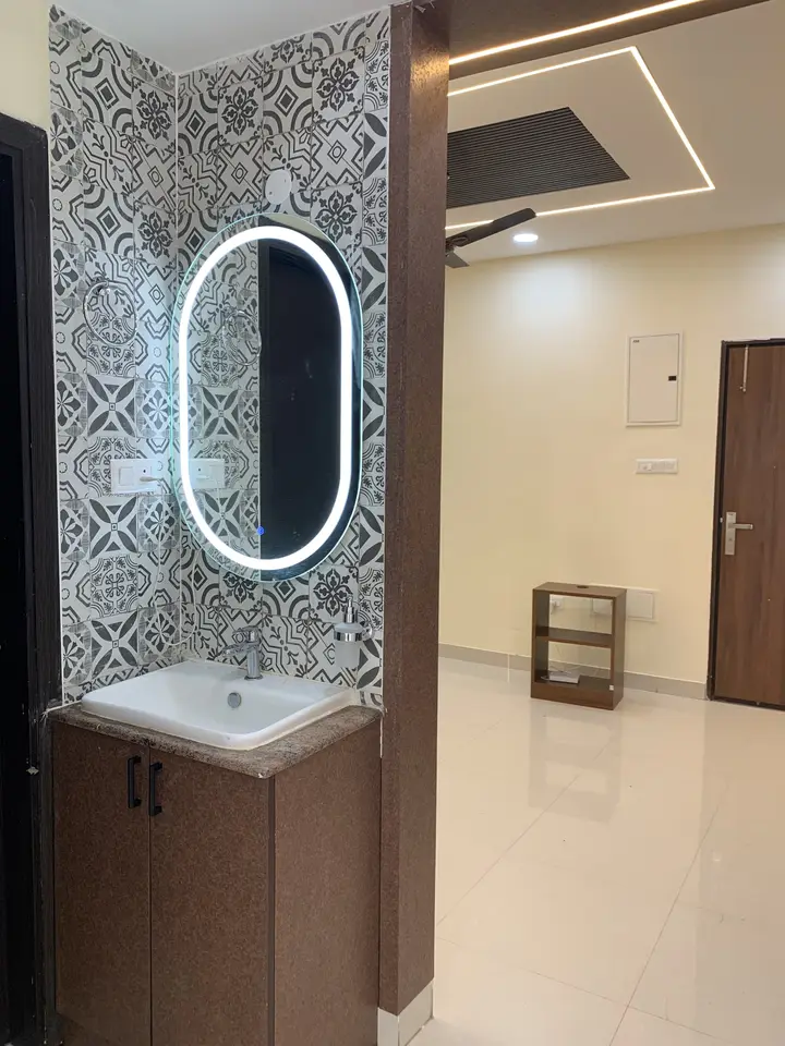 Vanity with an oval backlit mirror beside a timber panel