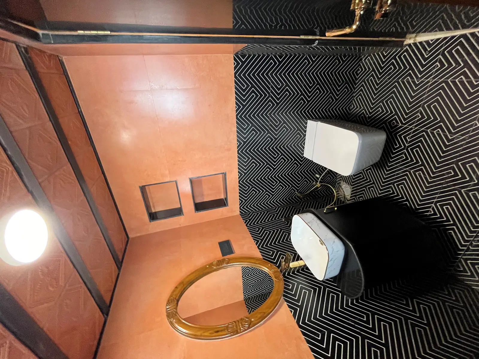 Black bathroom with brass fixtures and geometric floor tile