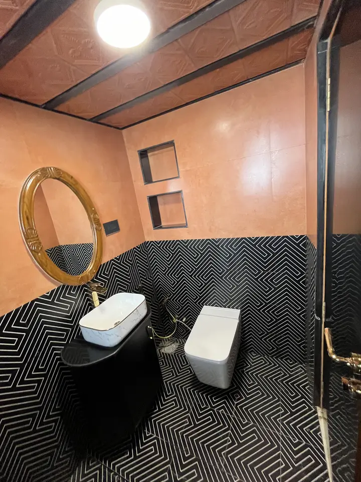 Powder room with a round mirror and black tile