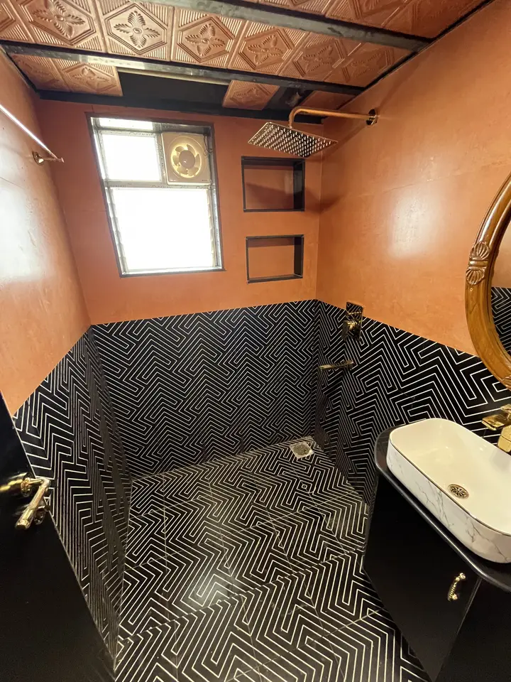Black tiled washroom with a terracotta wall