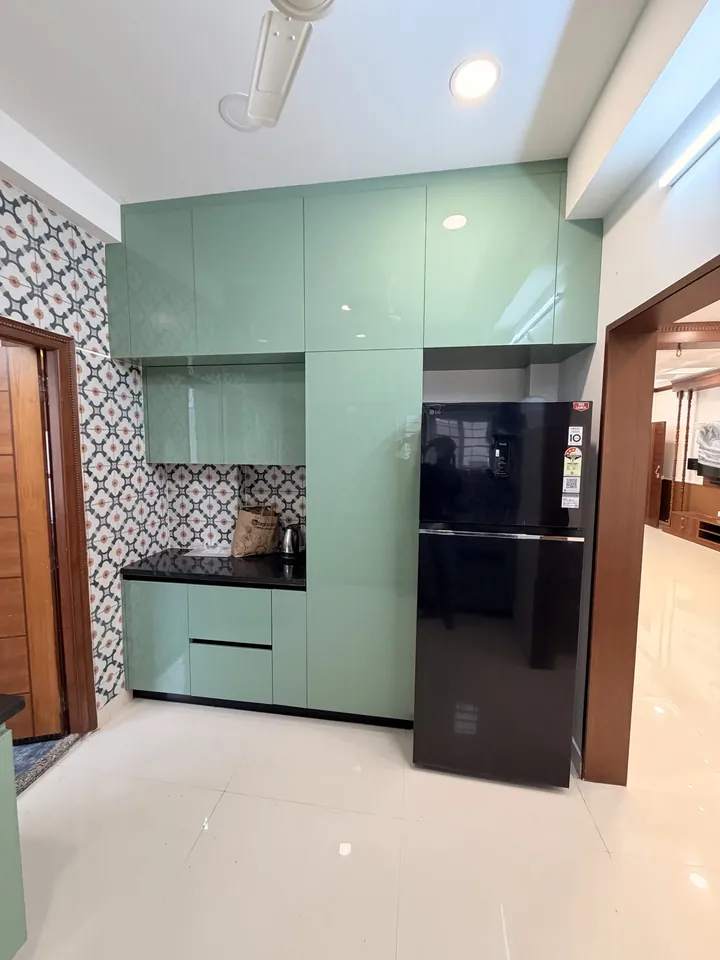Green kitchen cabinets beside the refrigerator