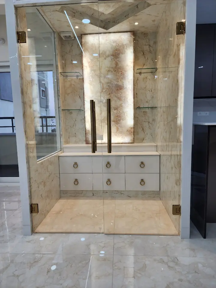 Marble-clad vanity niche behind a glass door