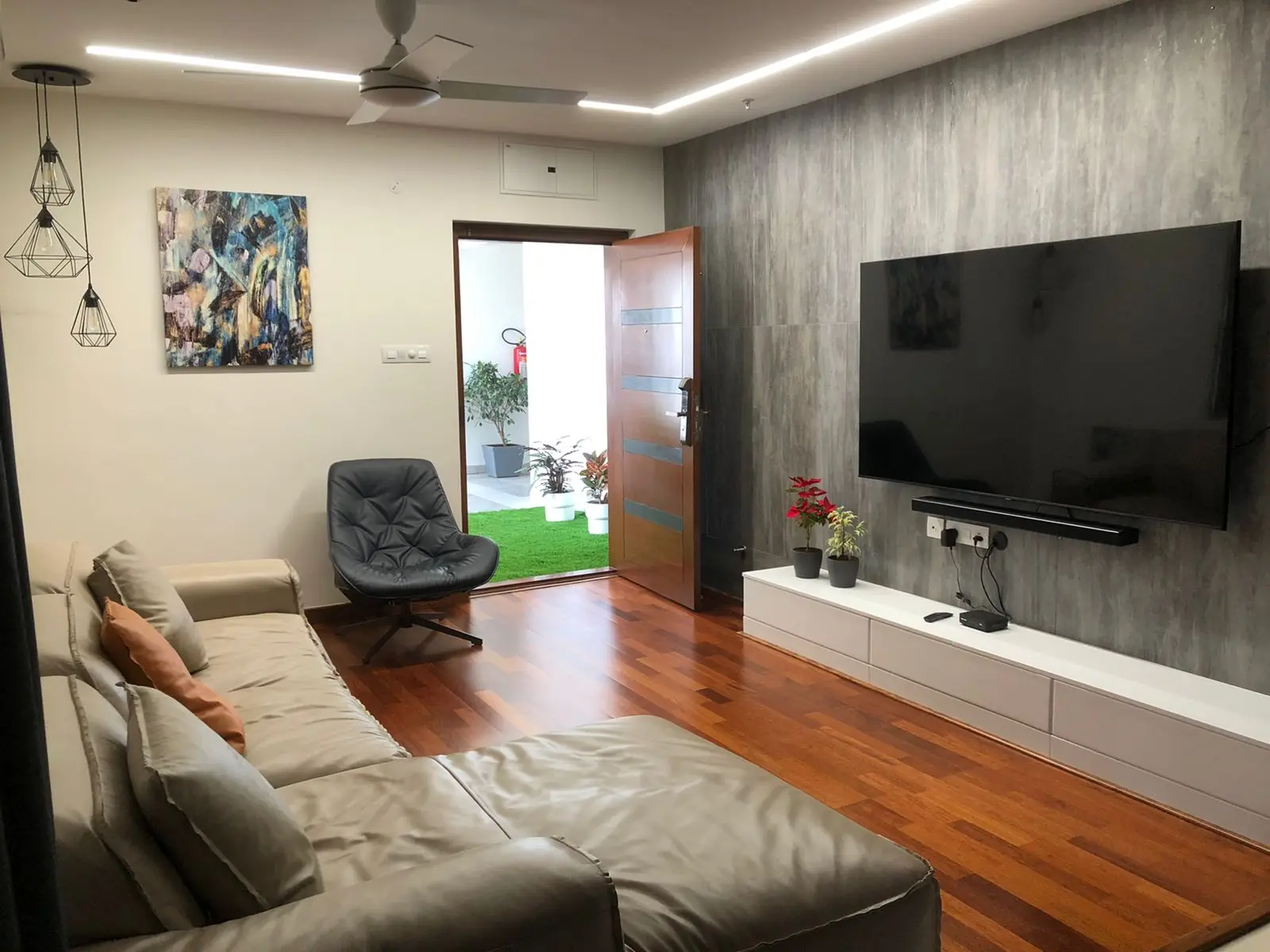 Living room with a leather sofa and grey TV wall on a timber floor