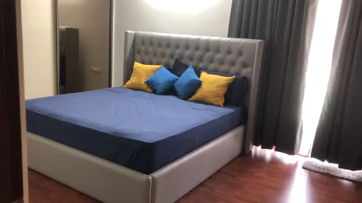 Bedroom with a grey upholstered headboard and blue bed