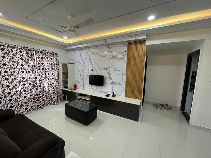 Living room with a white marble TV wall and patterned curtains