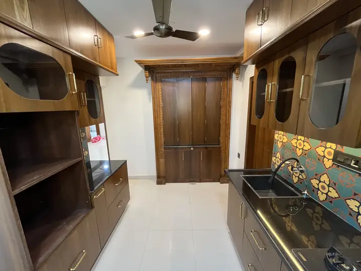 Living area with walnut cabinetry and a patterned-tile kitchen beyond