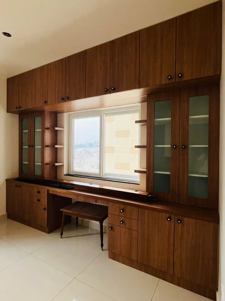 Walnut study desk with glass-fronted cabinets beside a window