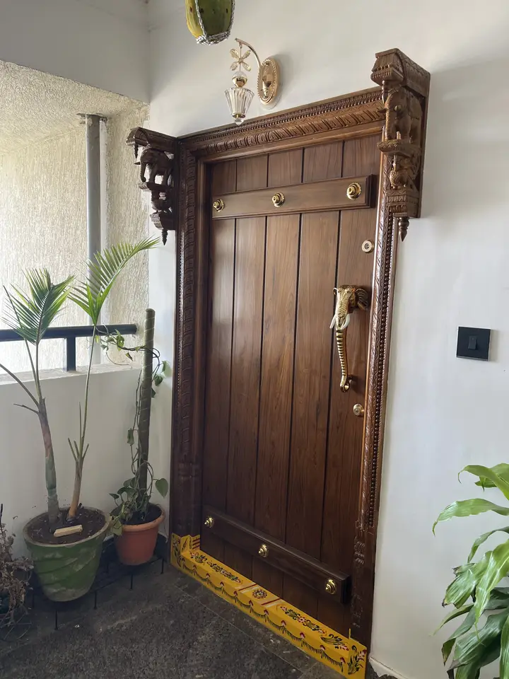 Timber entrance door with a carved frame and studded panels