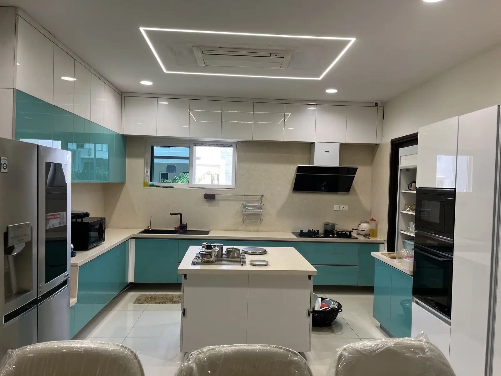 Teal and white kitchen with a central island under a lit ceiling