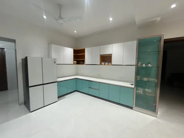 L-shaped teal and white kitchen with a tall fridge