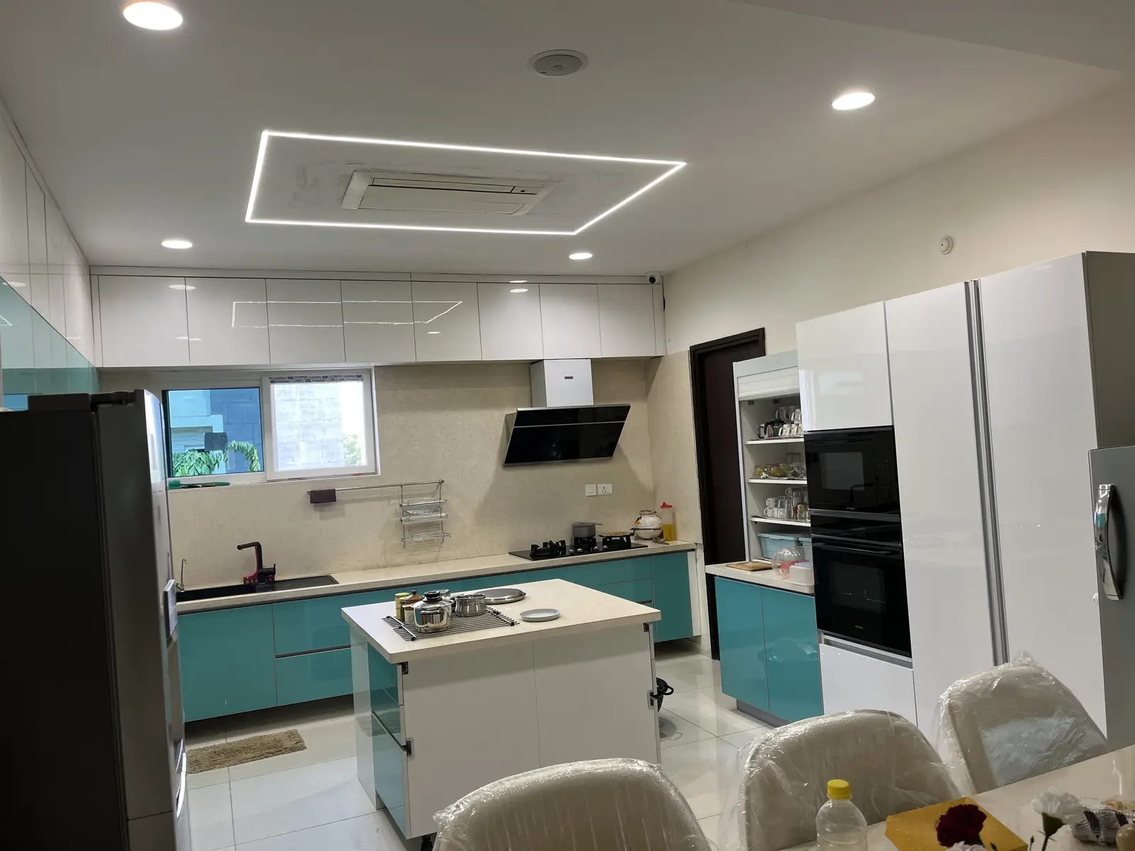 Kitchen island with teal base cabinets and tall black ovens