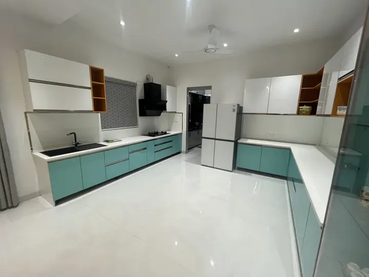 Kitchen with white overhead cabinets and teal glass-fronted units