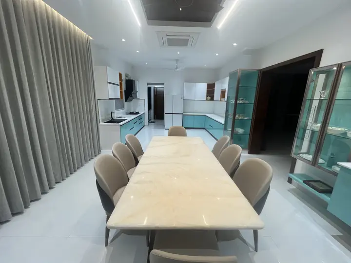 Long marble dining table with cream chairs and grey curtains