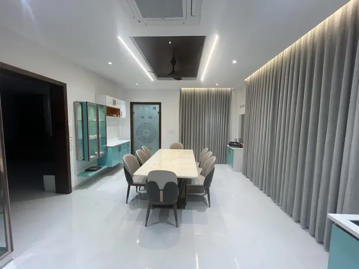 Dining table under a lit ceiling with a teal sideboard