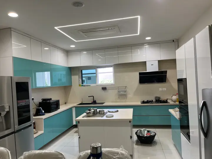 Teal and white kitchen with a lit island and tall ovens