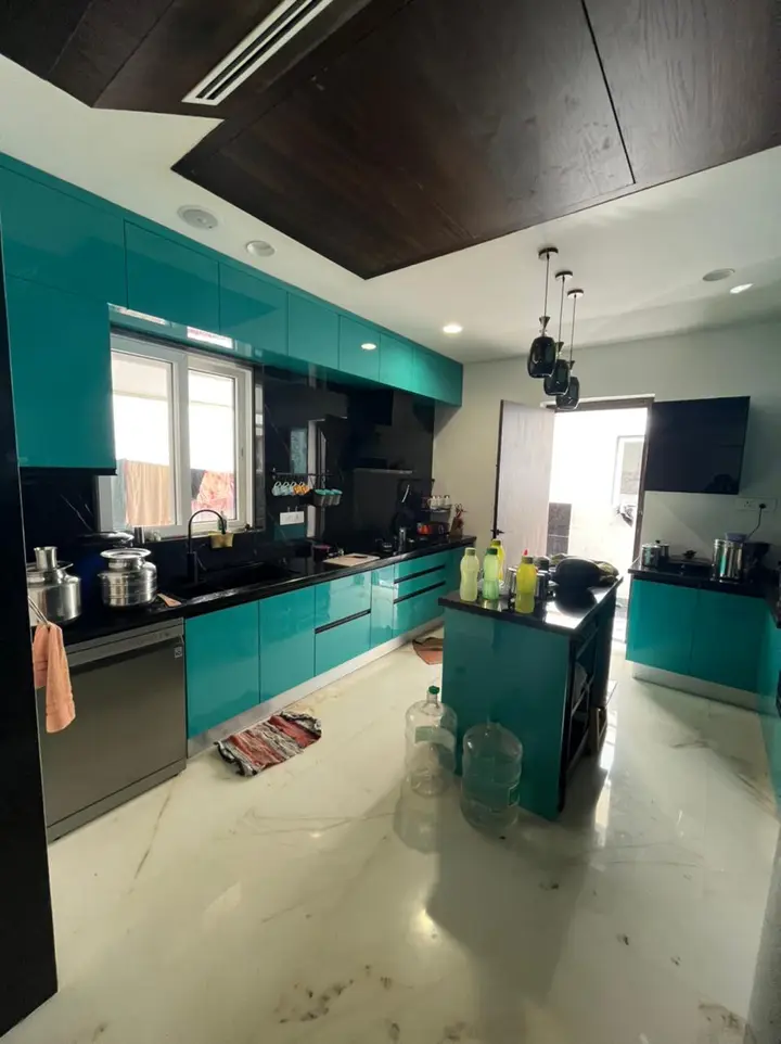 Teal kitchen with a black stone worktop