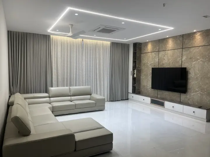 Corner sofa facing a stone-clad TV wall with grey curtains