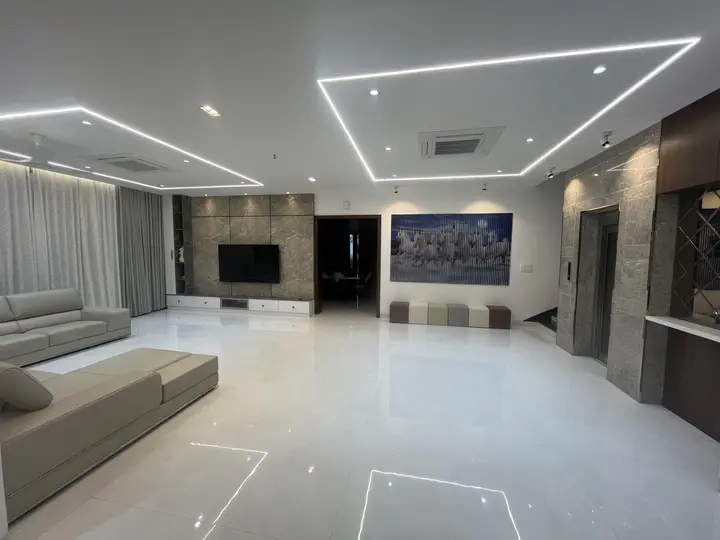 Wide view of the living room with a lit ceiling grid