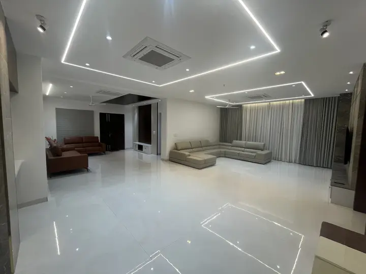 Wide living room with a tan sofa and recessed light lines