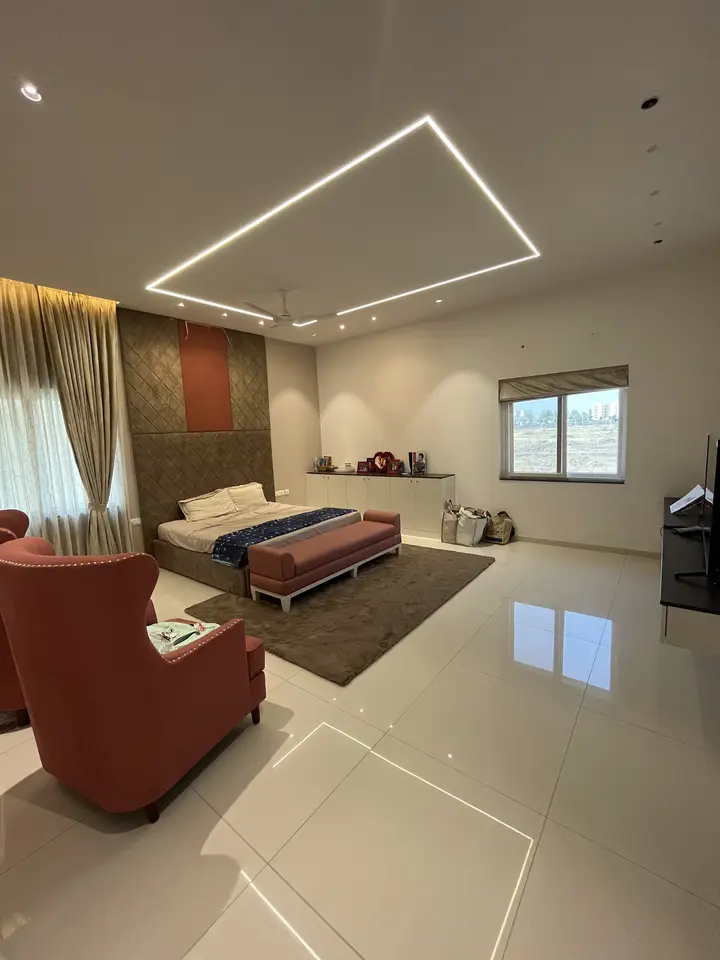 Bedroom with red armchairs and a lit ceiling frame