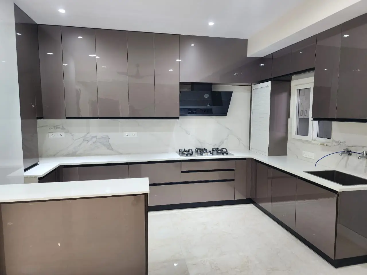 Taupe lacquer kitchen with white stone worktops and a built-in oven
