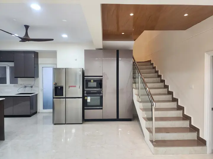Staircase beside a tall refrigerator and built-in ovens